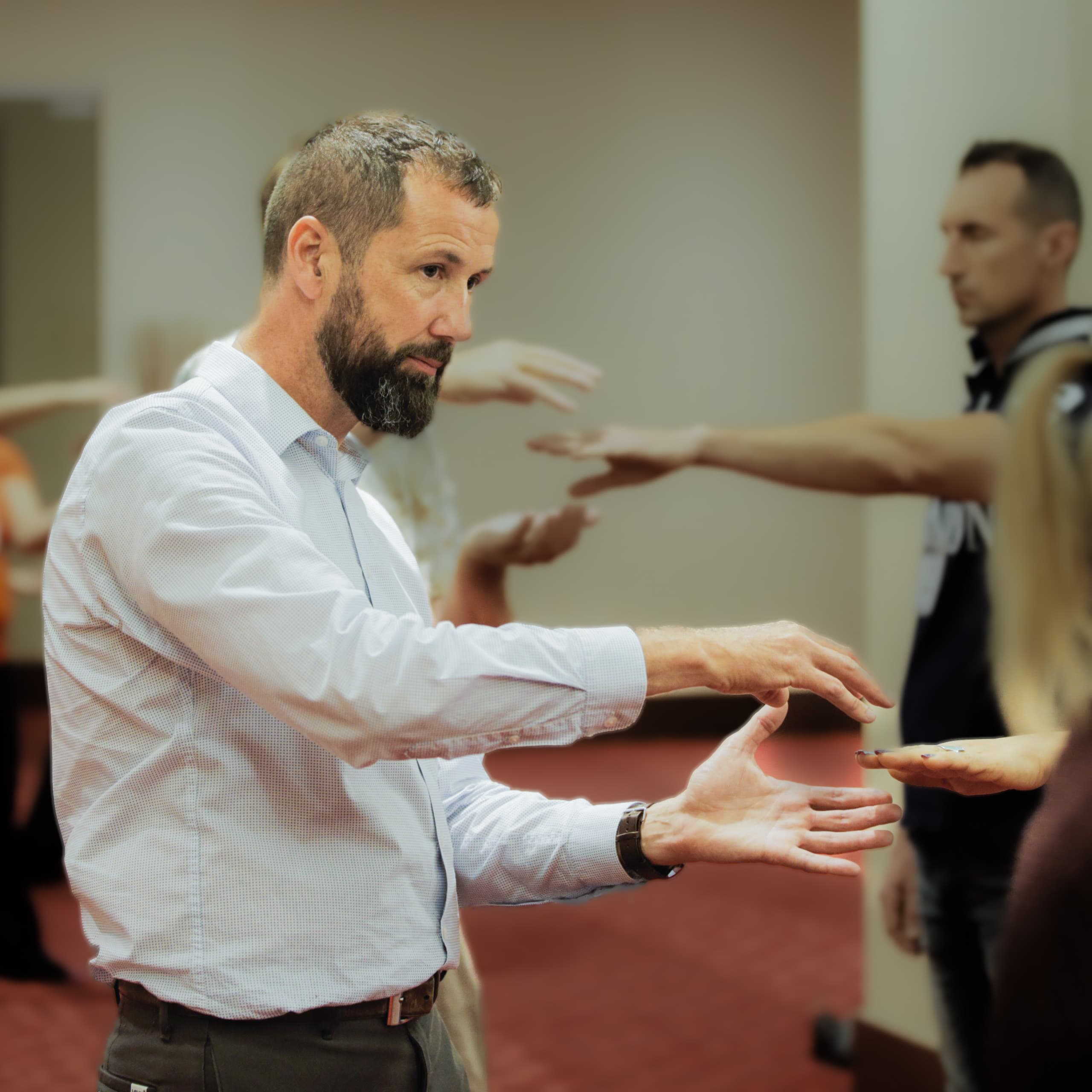 Michael D'Alton moving his hands above a seated student during a class